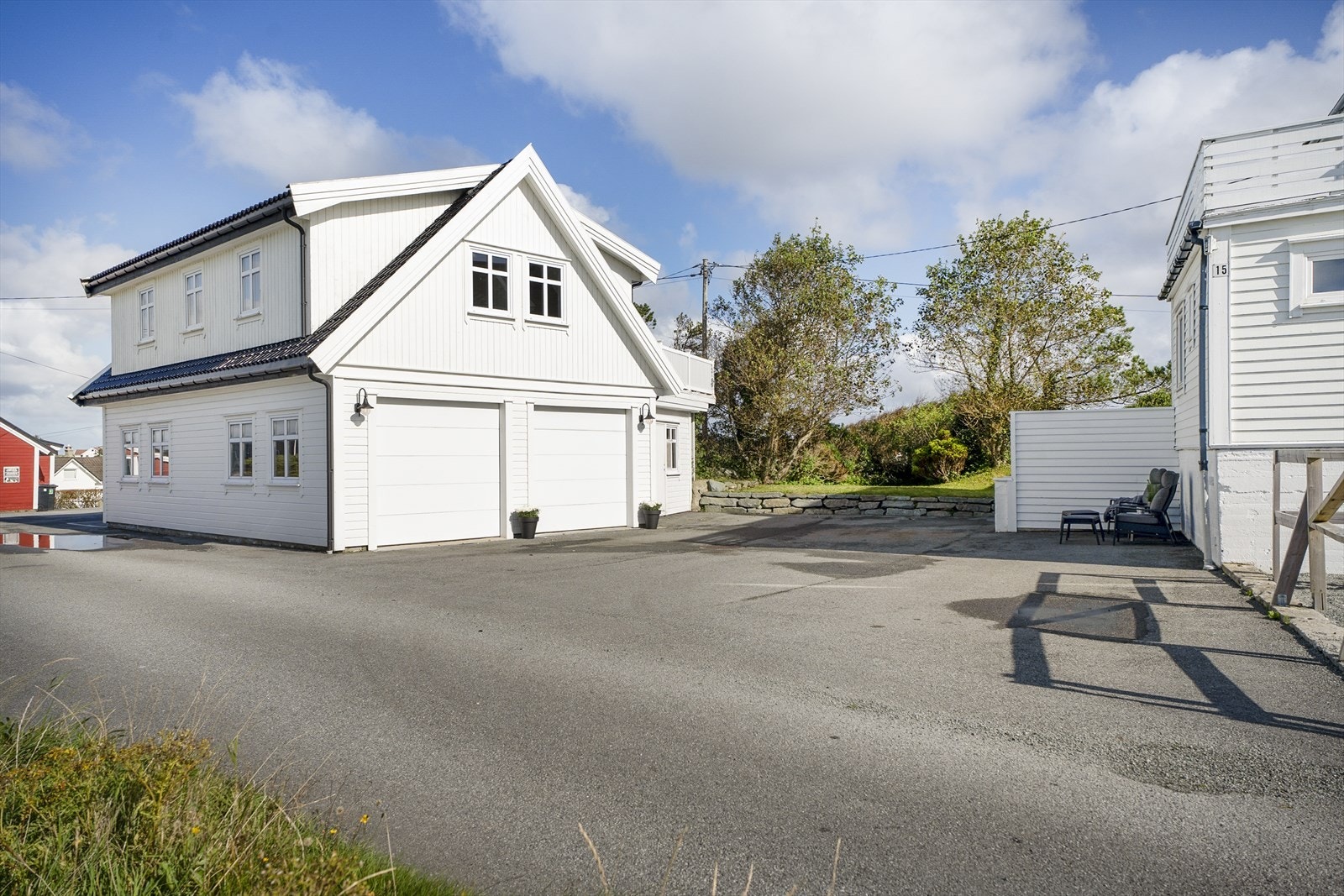 Asfaltert gårdsrom og stor garasje/stall med innredet loftsetasje. Galleribilde
