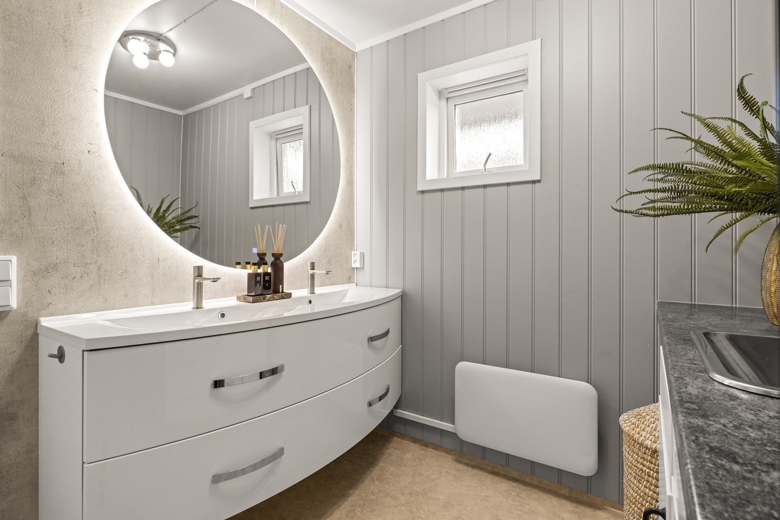 Badet har en praktisk og funksjonell utforming med MDF-panel på vegger og malt, slett tak. Bak servantskap er det montert våtromsplater av typen Fibotresbo, som gir beskyttelse mot fukt. Galleribilde