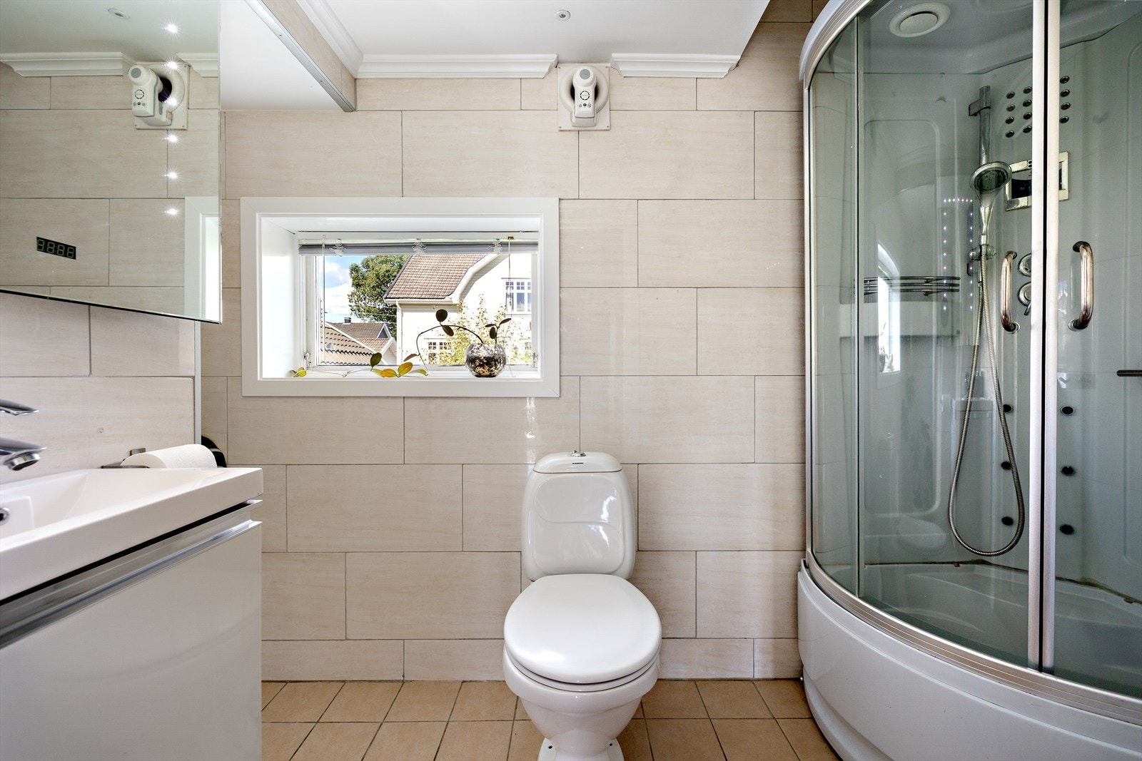 Det er også opplegg for vaskemaskin, noe som gjør rommet funksjonelt i hverdagen. Komforten ivaretas med elektriske varmekabler i gulvet, og både elektrisk vifte i vegg og tilluft via dør sørger for god ventilasjon. Galleribilde