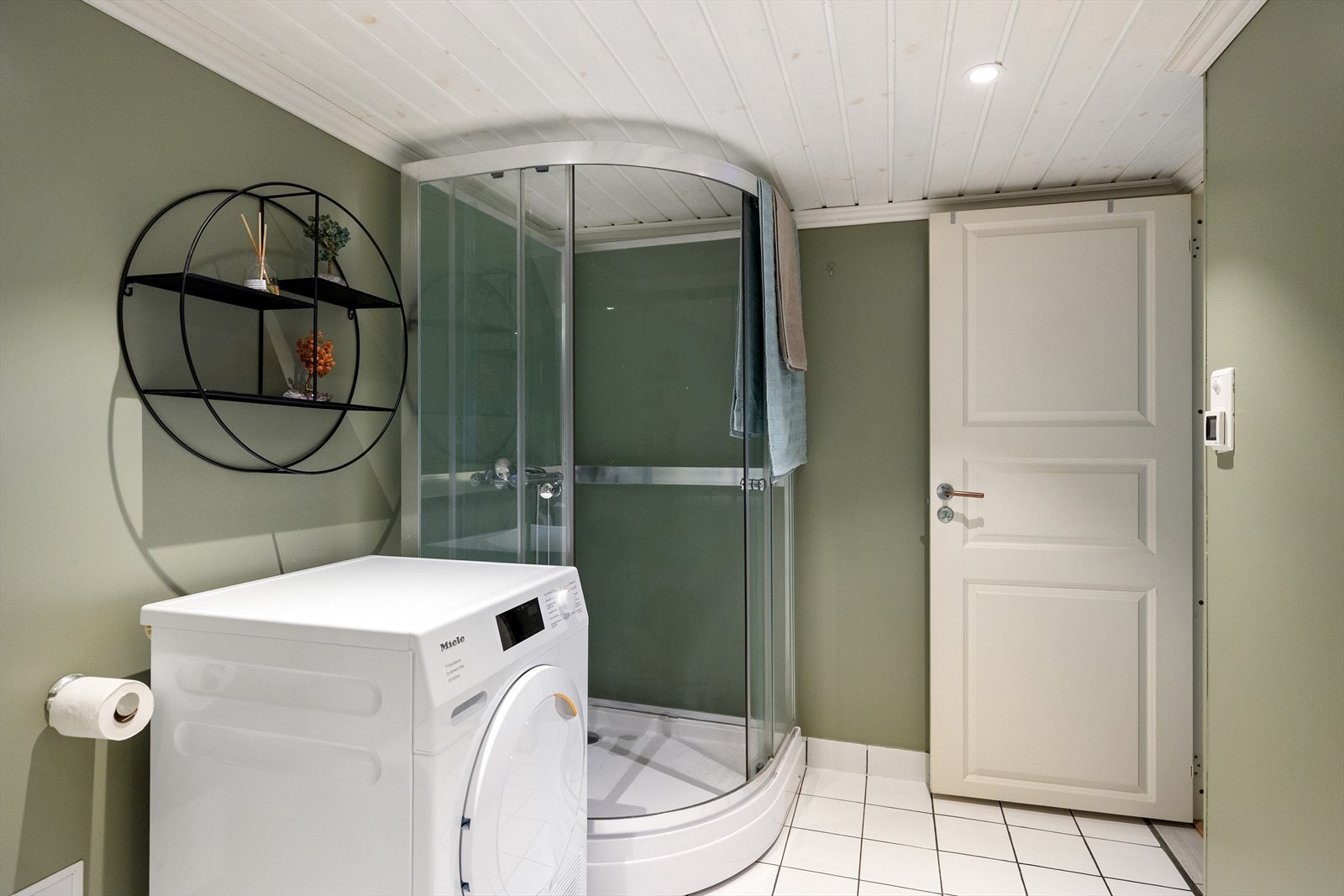 Baderommet er innredet med dusjkabinett, toalett, servantskap med oppbevaringsplass, speil og hylle. I tillegg er det opplegg for vaskemaskin. Komforten ivaretas med elektriske varmekabler i gulvet.. Galleribilde