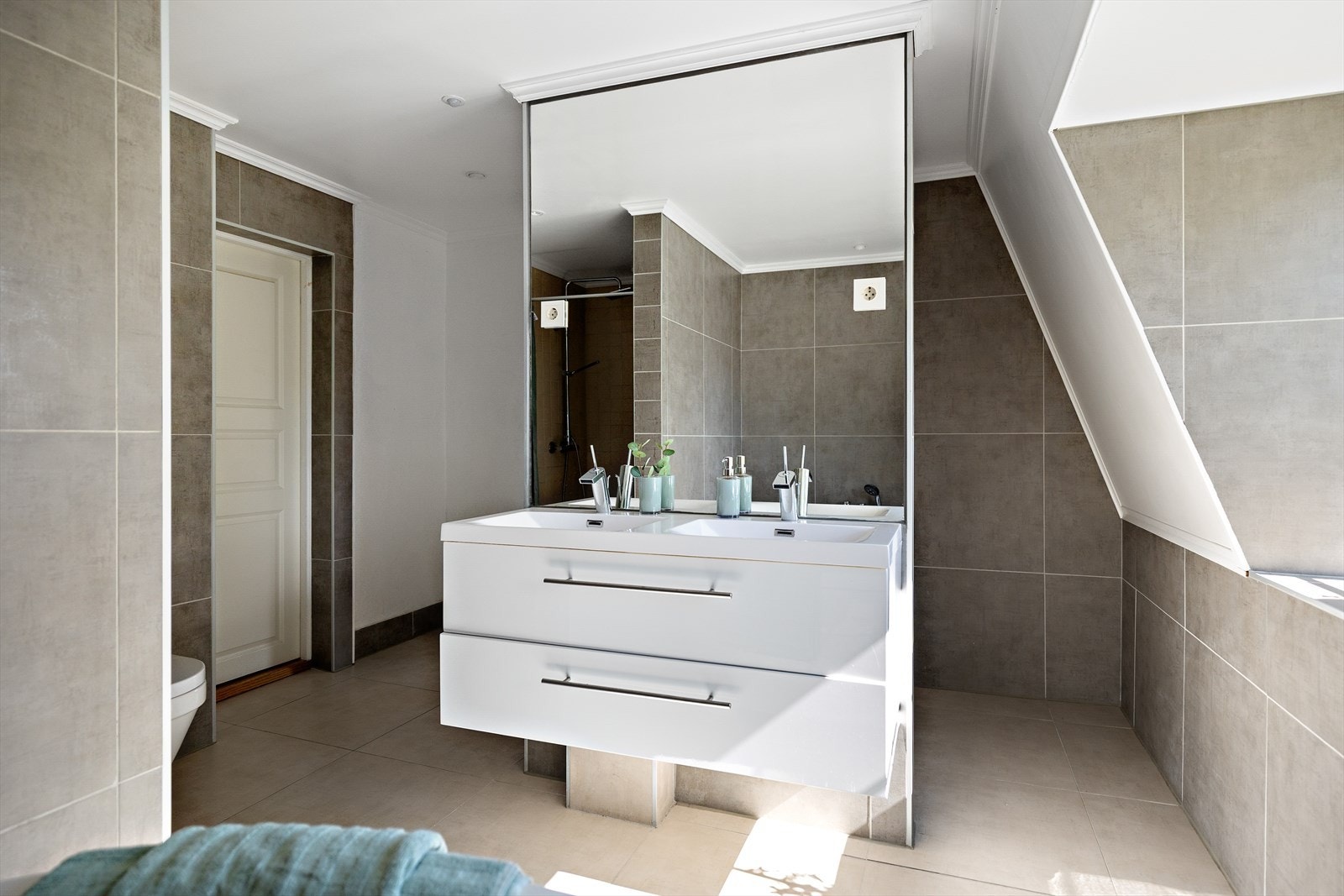 Hovedbadet i 2. etasje er et rom som virkelig inviterer til hverdagsluksus. Med sin romslige utforming er det tilrettelagt for både funksjonalitet og velvære. Galleribilde