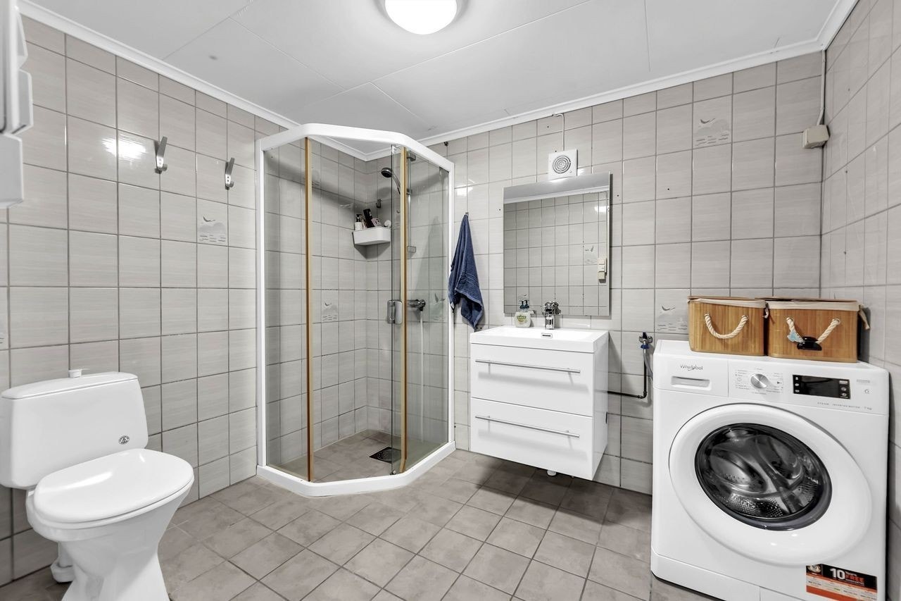 Flislagt baderom med gulvvarme og opplegg for vaskemaskin og trøketrommel Galleribilde