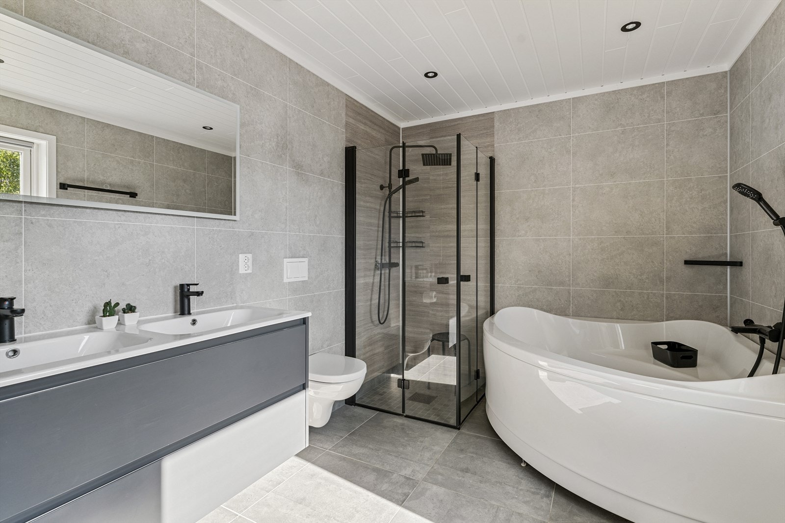 Du har også eit eige baderom til hovudsoverommet. Med hjørnebadekar, dusj på flislagt golv med innfellbare dusjdører, vegghengt toalett og dobbel, heilstøypt servant innreiing. Galleribilde