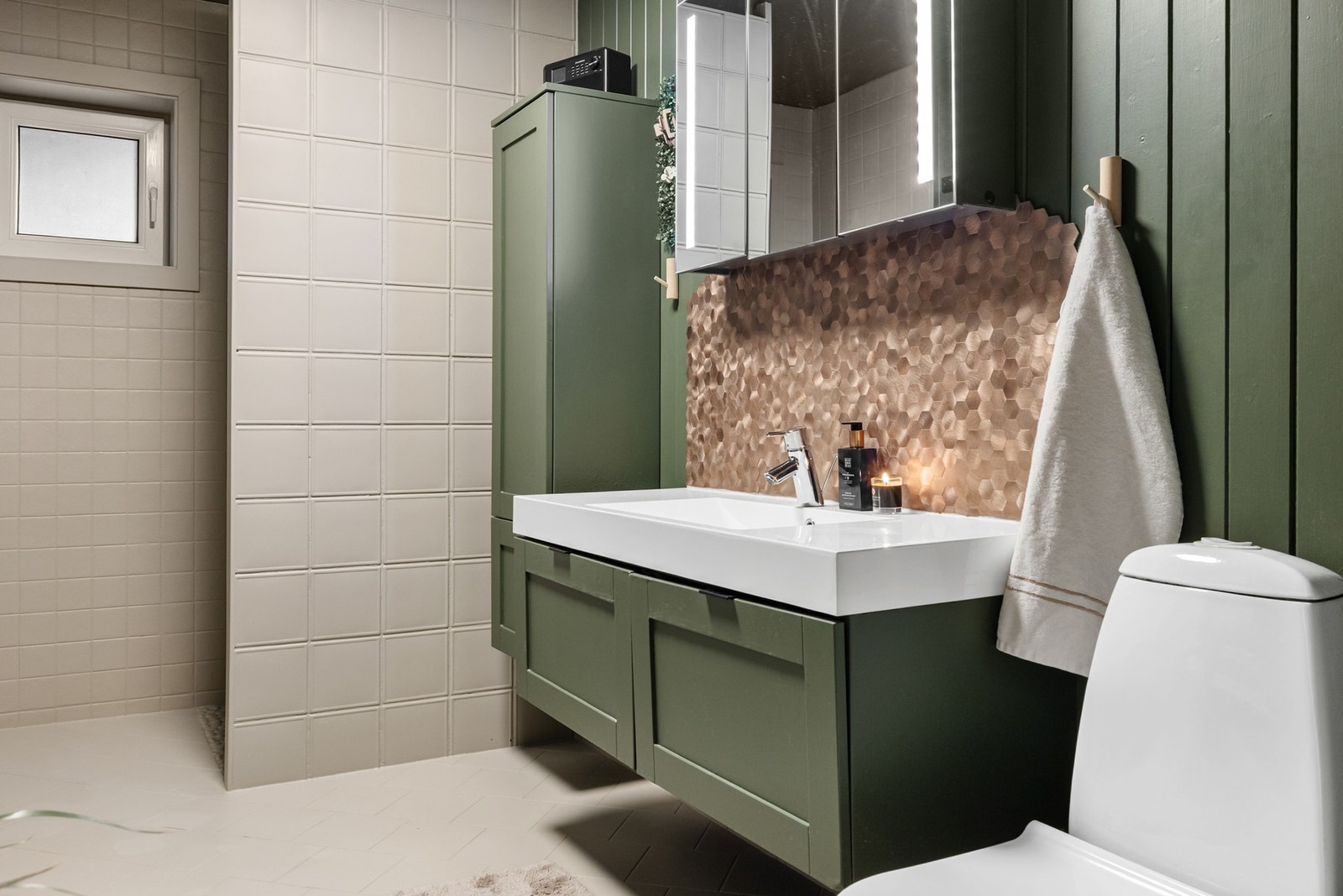 Innredet med skuffeinnredning med heldekkende servant, speilskap med innfelt belysning, toalett og dusjsone. Galleribilde