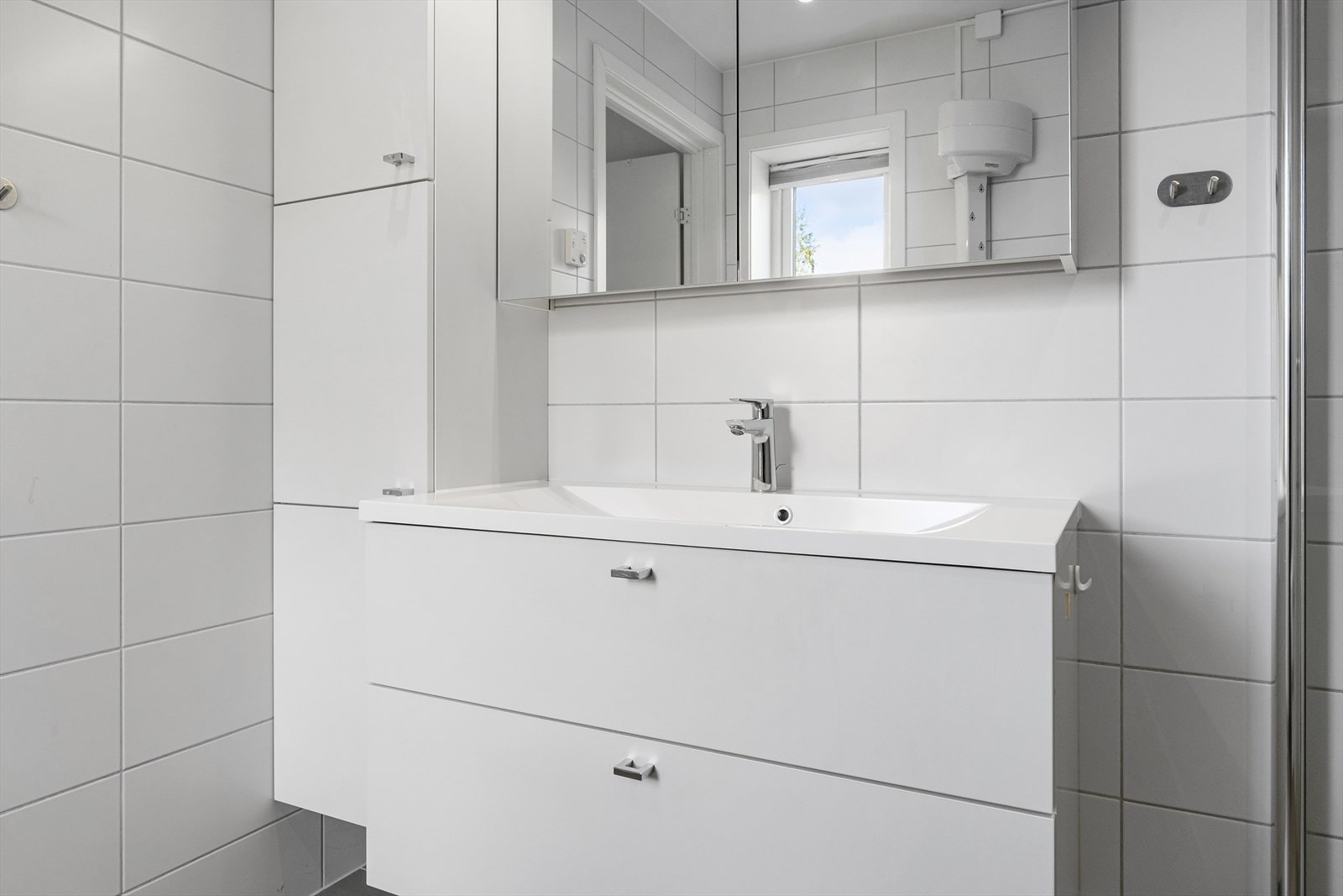 Badet er innredet med servantskap med helstøpt servant, speilskap med belysning over, høyskap, toalett og dusjhjørne. Galleribilde