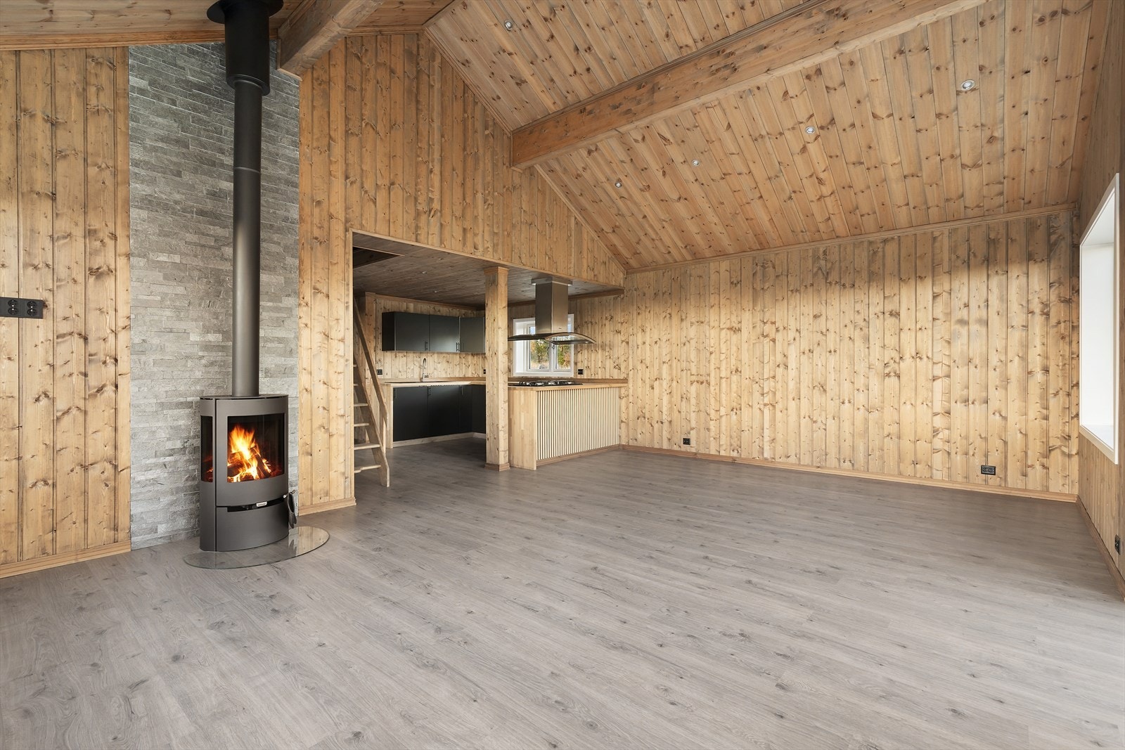 Beiset trepanel i både tak og vegger skaper en varm og rolig atmosfære i oppholdsrommet, mens 1-stavs laminat på gulv og gjennomført bruk av naturlige materialer gir et helhetlig uttrykk. Galleribilde