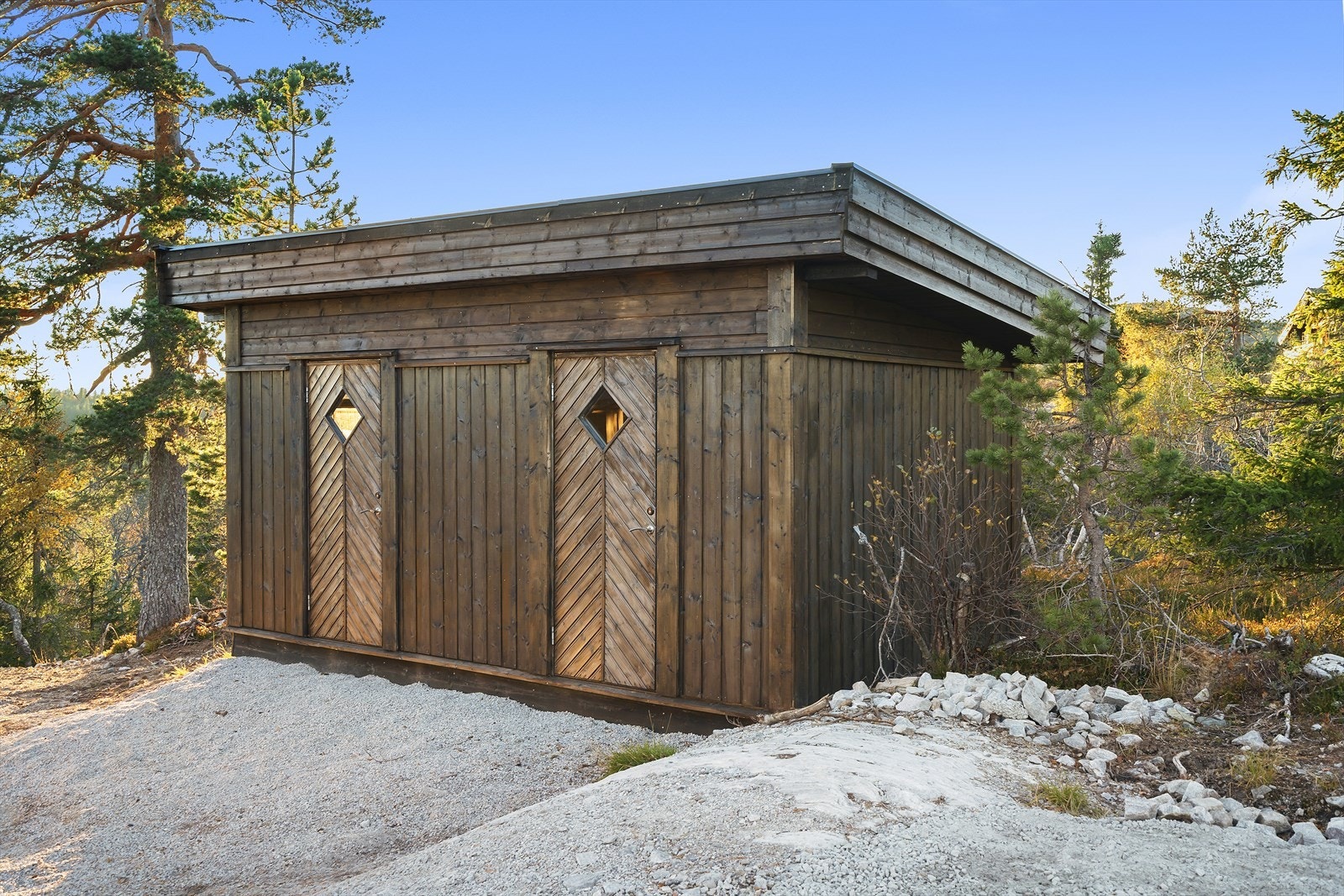 Praktisk utebod med solid bindingsverkskonstruksjon og stående trekledning i samme stil som hytta. Galleribilde