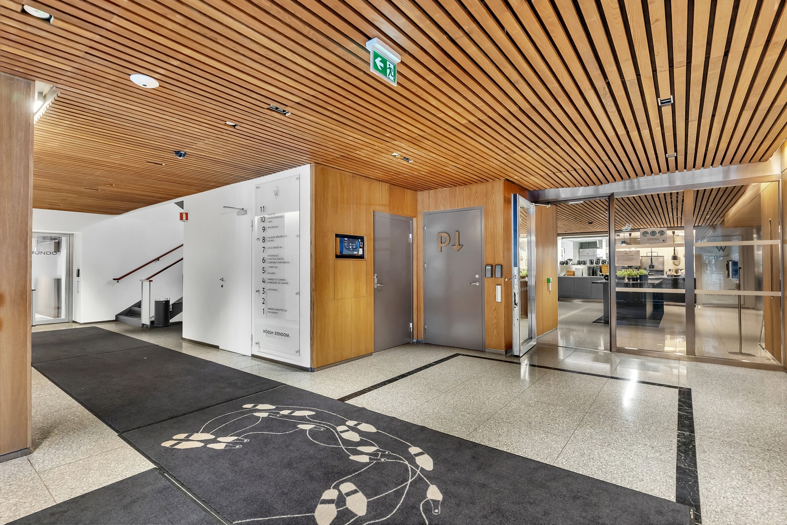 Romslig inngangsparti med heis og trapp, samt inngang til personalrestaurant Galleribilde