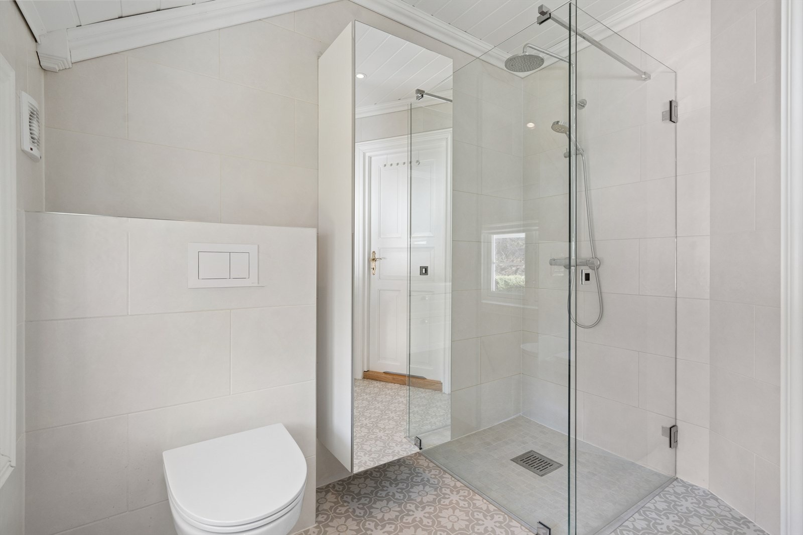 Rommet er innredet med baderomsinnredning med skuffeseksjon, speilskap, vegghengt toalett og veggskap med speil. Videre er det en stor og herlig dusjsone med hel glassvegg og glassdør, med montert rainshower for ekte "spafølelse" i hverdagen. Galleribilde