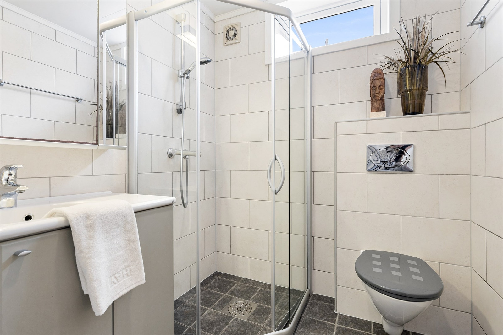 Vegghengt høyskap ved siden av servant. Dusjsone med delvegger og skyvedør av glass. Dusjarmatur tilkoblet hånddusj. Vegghengt toalett. Elektrisk avtrekksvifte på yttervegg. Vannrør av kobber. Synlige avløpsrør av plast. Galleribilde