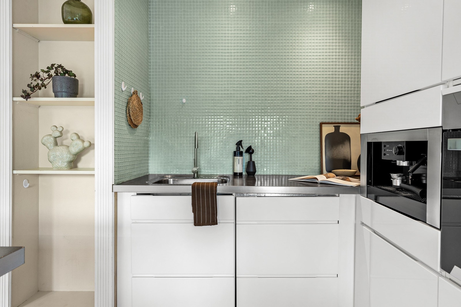 Vannrør av kobber. Synlige avløpsrør av plast. Kjøkkenet har montert komfyrvakt. Galleribilde