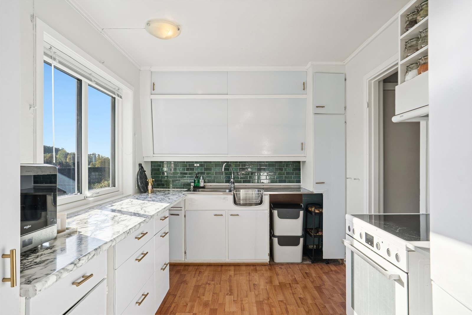 Lys kjøkkeninnredning av eldre dato, med plass til frittstående komfyr og kjøl/frys. Galleribilde