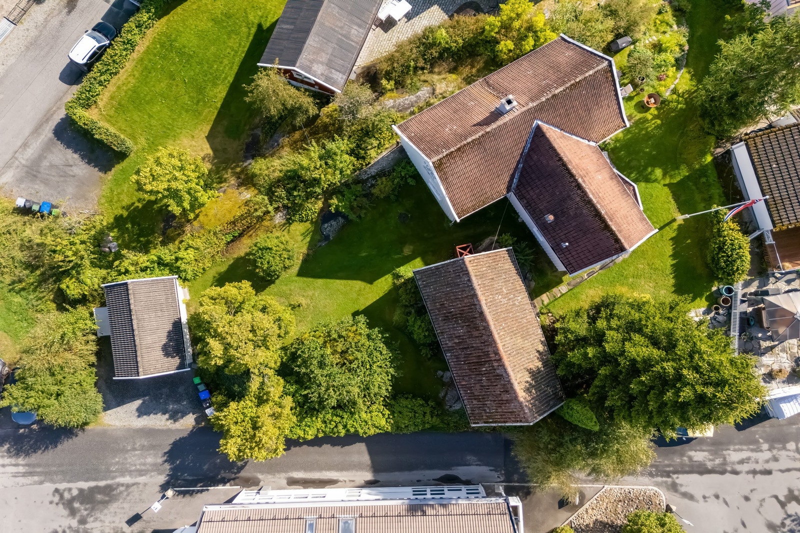 Oversiktsbilde av eiendommen bestående av garasje, uthus, bod med takterrasse og enebolig. Galleribilde