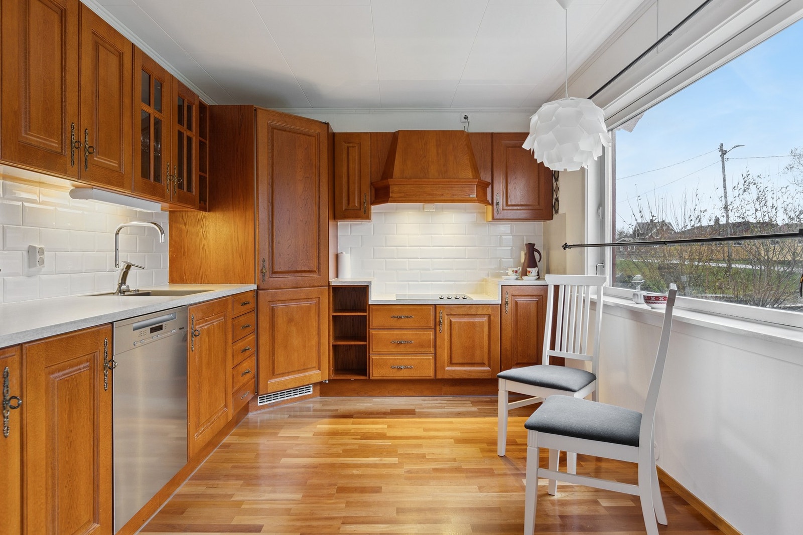 Innredningen i vinkel byr på integrerte hvitevarer, kjølehjørne og fliser mellom over- og underskap. Galleribilde