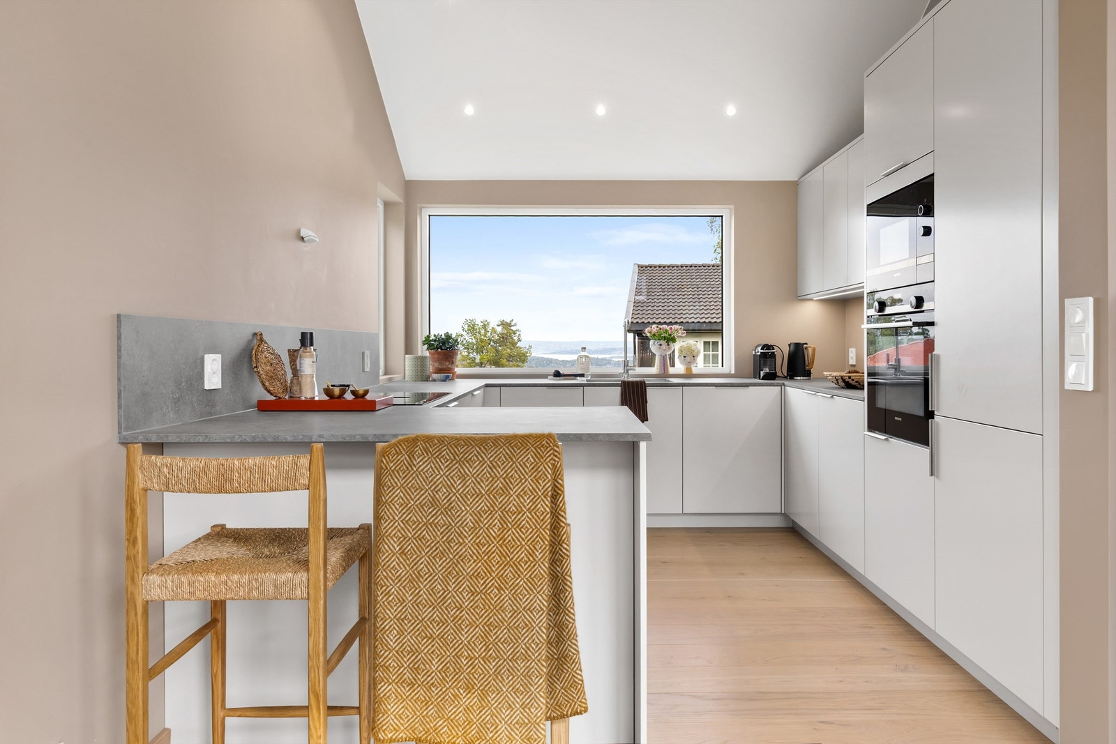 Moderne og stilrent kjøkken med integrerte hvitevarer og fantastisk utsikt mot fjorden. Galleribilde