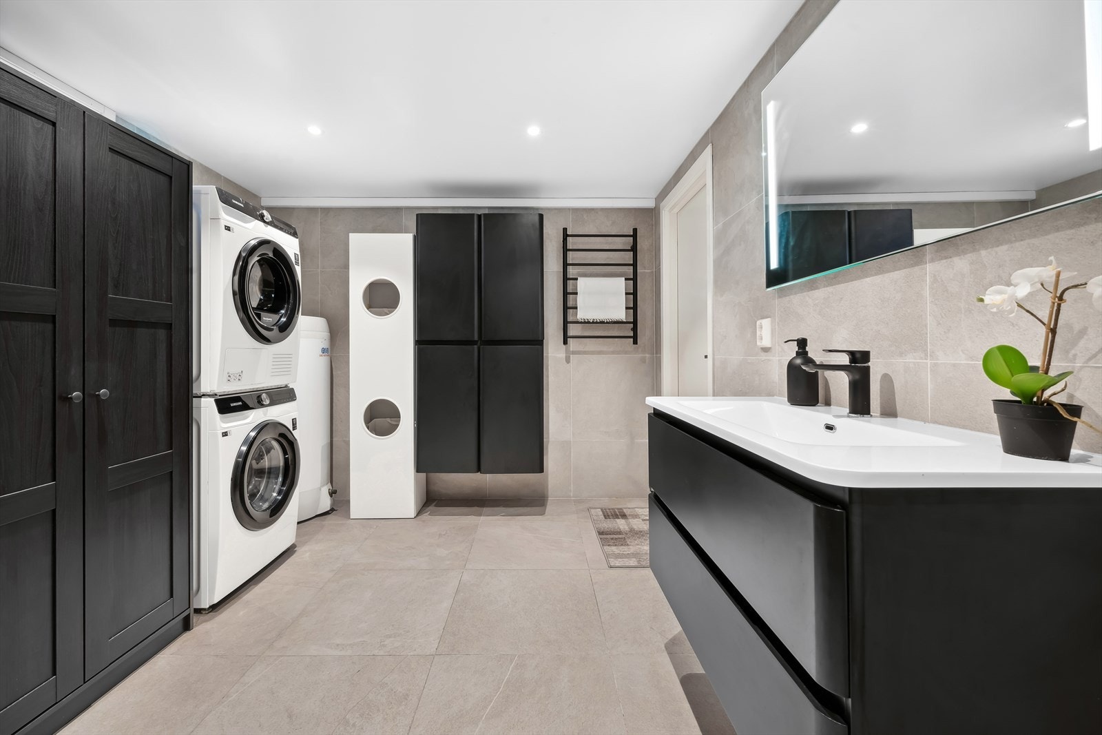 Innredningen har slette fronter og en heldekkende servant med ett-greps blandebatteri og plastavløp. Det er opplegg for vaskemaskin og tørketrommel, og badet har et vegghengt toalett. Galleribilde