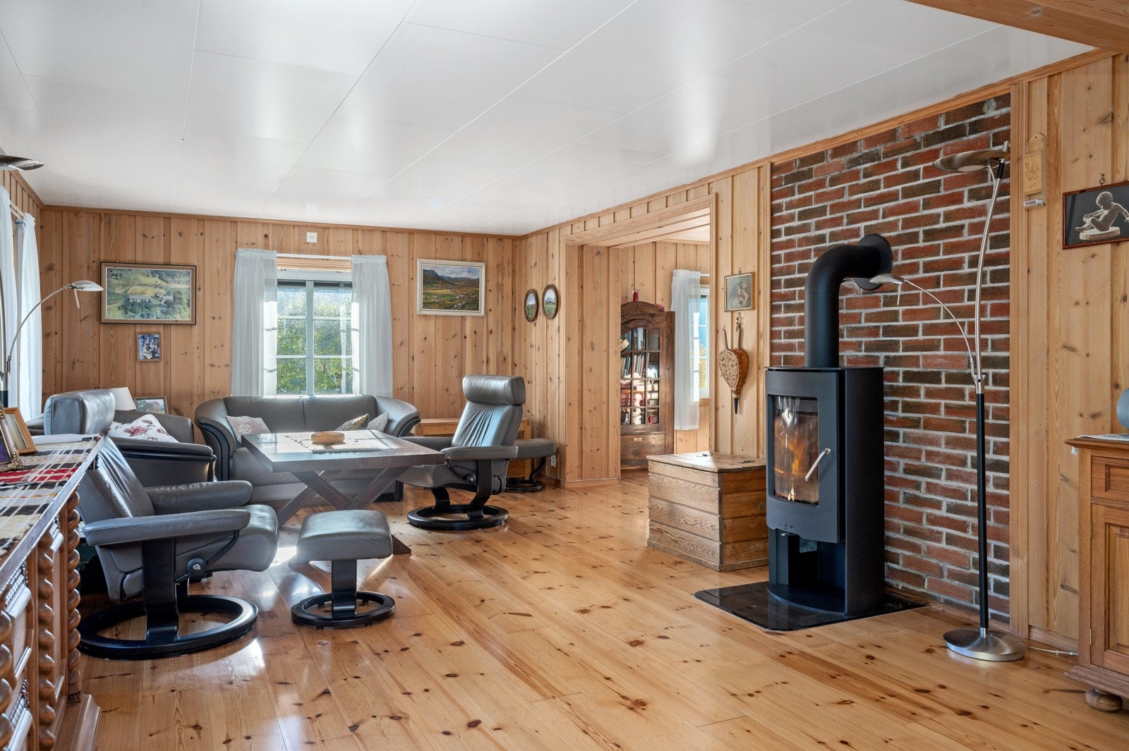 Kårboligen har en innbydende stue med store vinduer og stemningsfull peisovn. Galleribilde