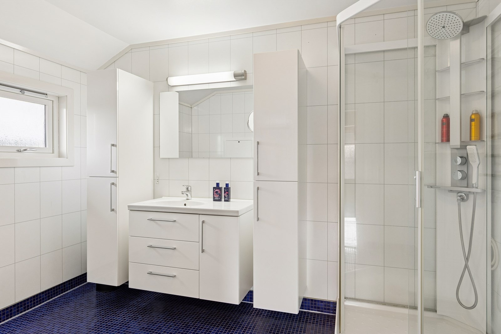 Baderommet i andre etasje ble modernisert i 2009 og er innredet med blå mosaikkfliser på gulv og hvite baderomsplater på vegg. Også her har man varmekabler i gulvet. Galleribilde