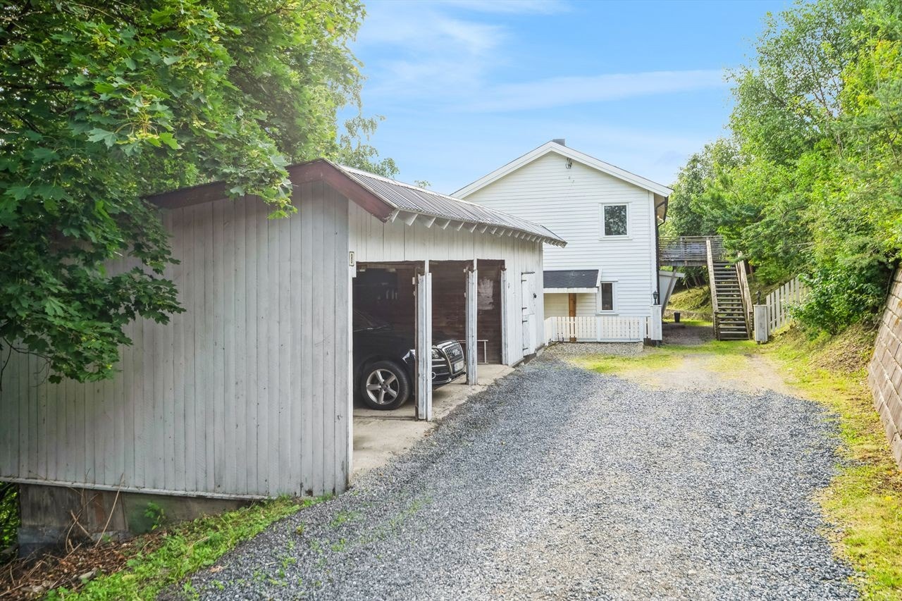 Gruset gårdsplass med uthus som har plass for tre biler samt bodplasser. Galleribilde
