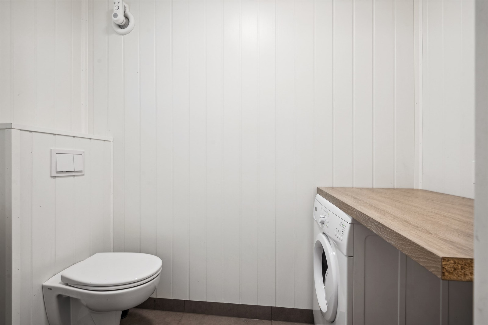 Vaskerom fra 2020 med malte plater på vegger. Gulvet er flislagt med elektriske varmekabler. Det er opplegg for vaskemaskin og veggmontert toalett. Galleribilde