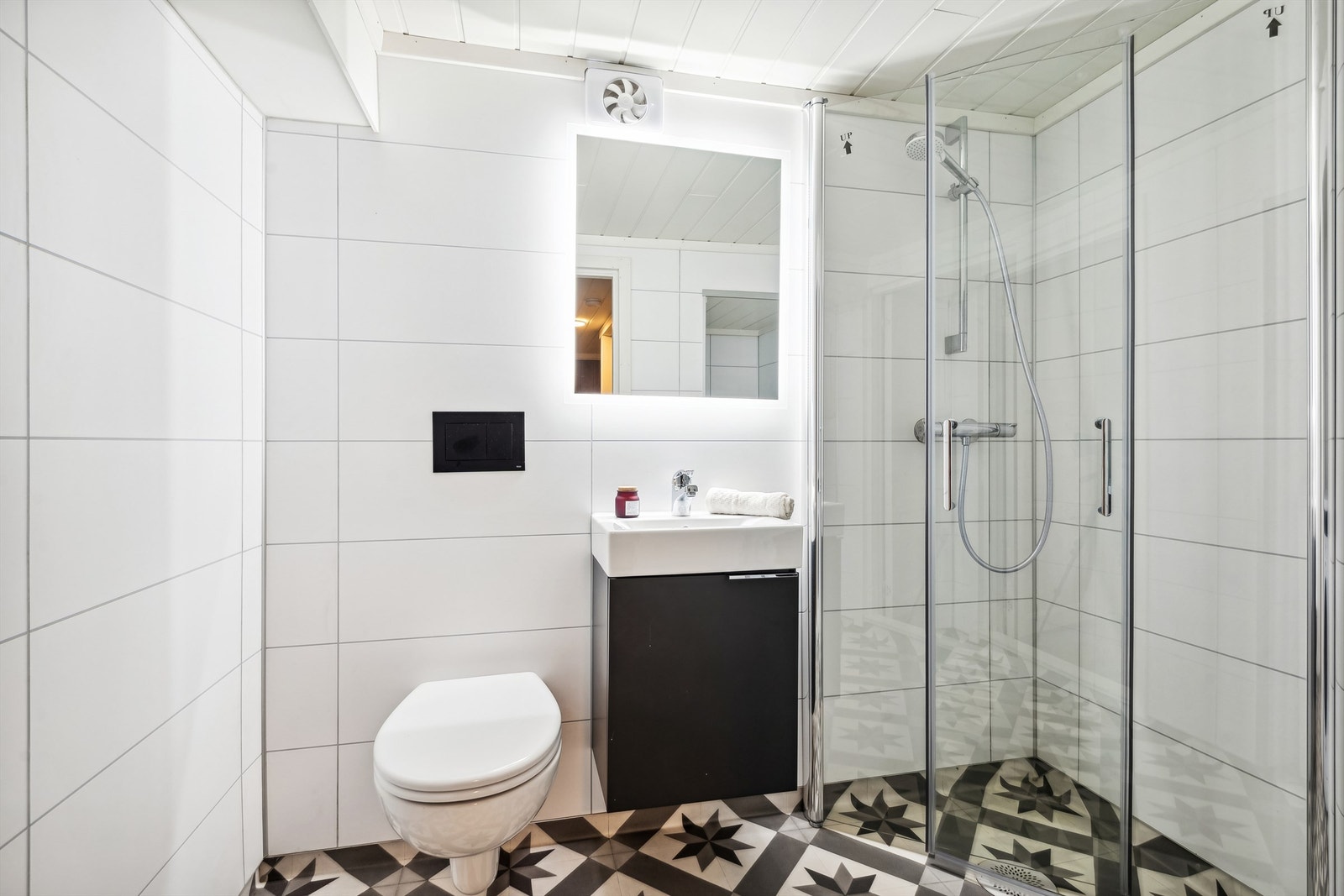 Pent bad som er oppusset i 2020. Vegger med baderomsplater og vinylbelegg på gulv med elektriske varmekabler. Praktisk nedfelt servant, speil med lys og dusjhjørne. Galleribilde