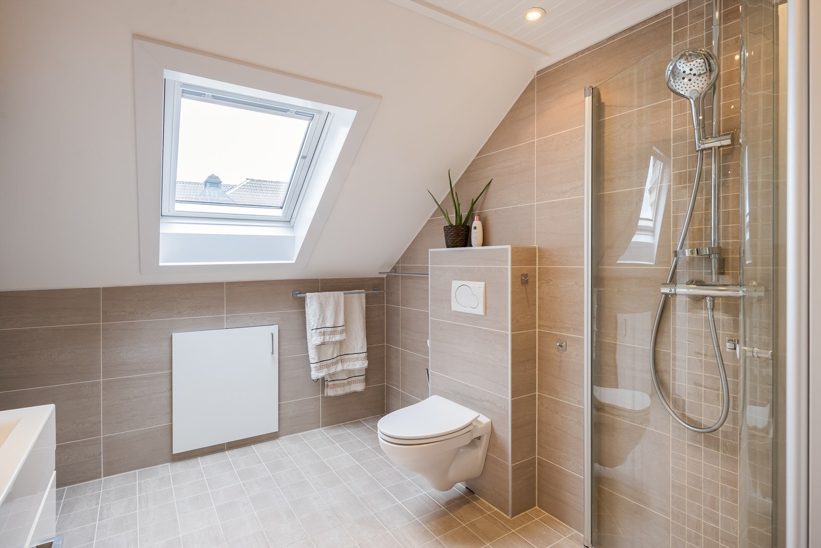 Badet er utstyrt med dusjvegger i glass og dusjgarnityr på vegg, vegghengt toalett, vegghengt servant samt opplegg for vaskemaskin. Galleribilde