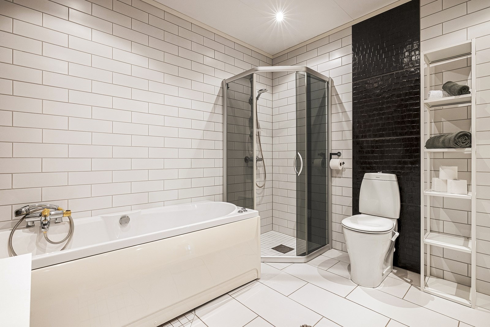 Badet er innredet med servant i møbel, toalett, badekar og dusj med skyvedør. Galleribilde