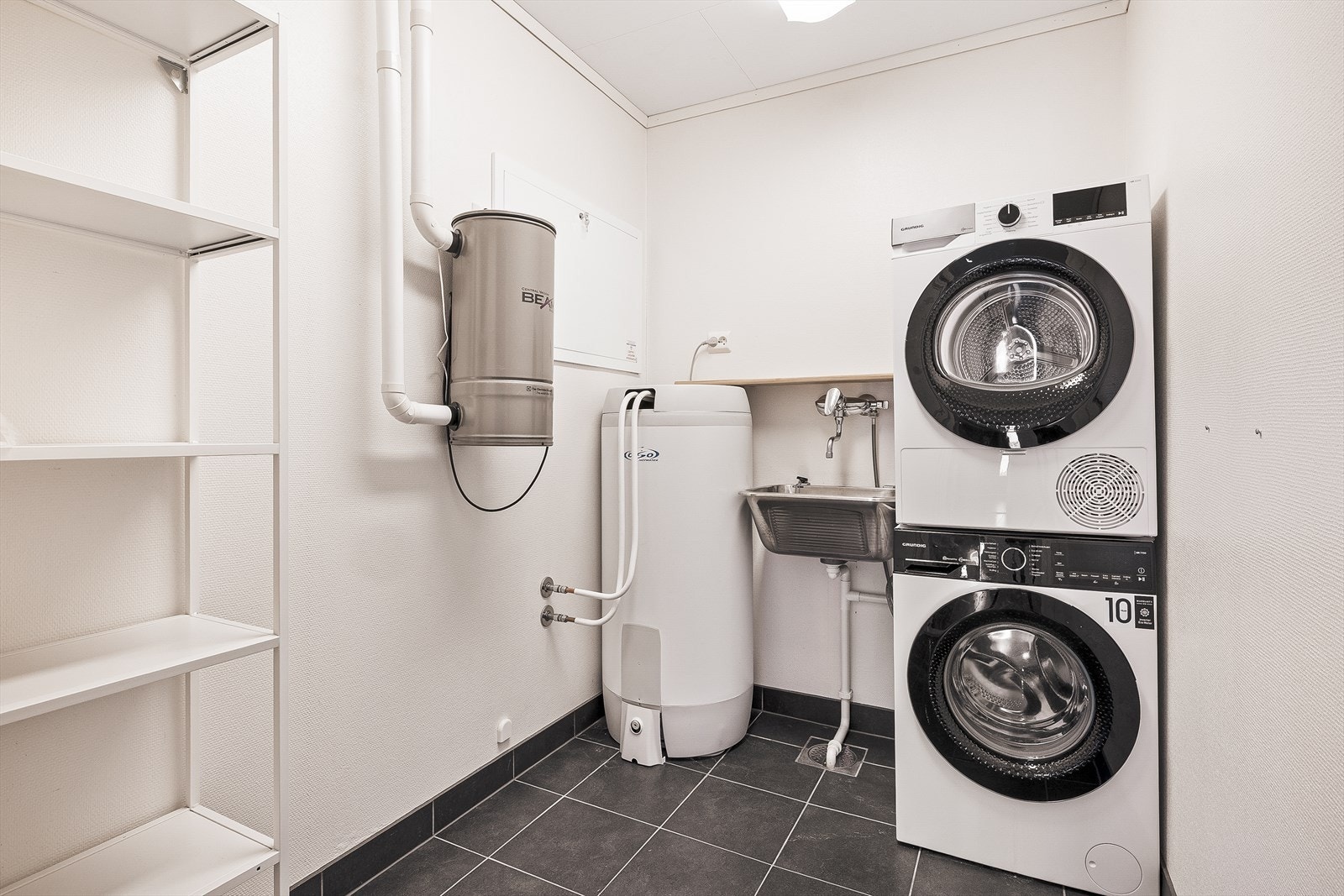 Praktisk vaskerom med opplegg for vaskemaskin, utslagsvask, varmtvannsbereder og sentralstøvsuger. Galleribilde