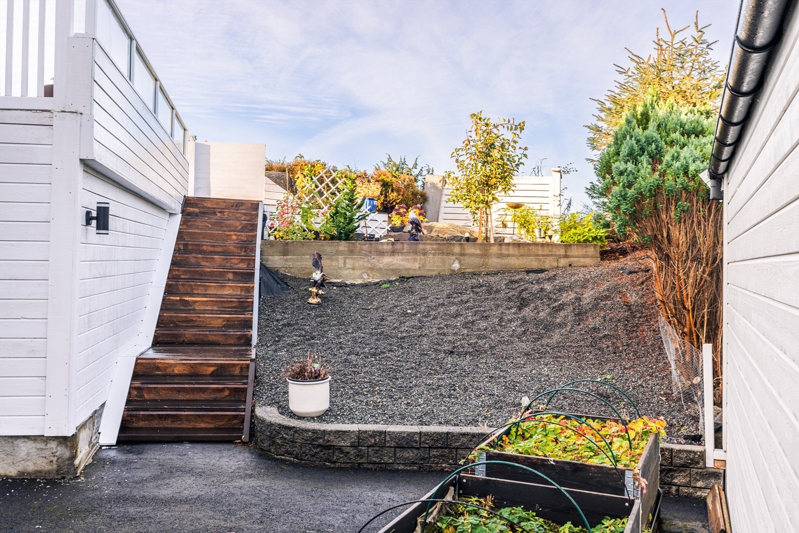 Ved siden av garasjen fører en trapp opp til terrassen, samt et delvis gruslagt og beplantet uteareal. Galleribilde