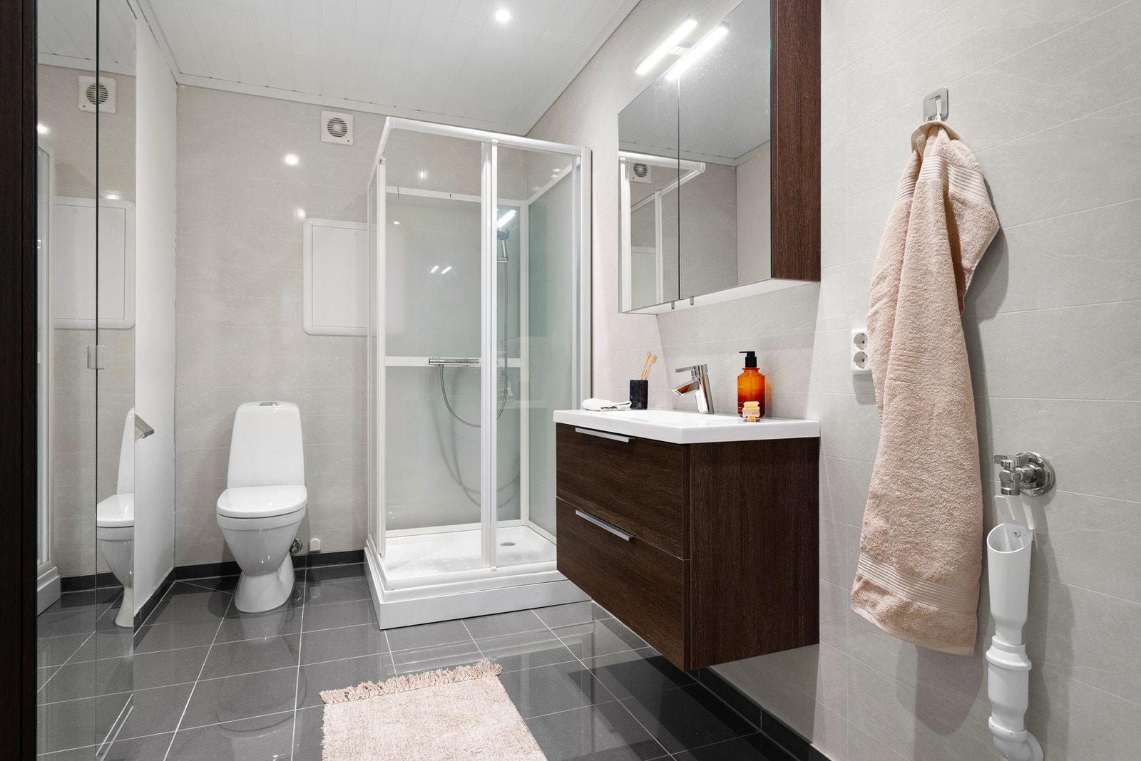 Pent baderom fra ca. 2018 med servant, toalett, dusjkabinett og opplegg for vaskemaskin. Galleribilde