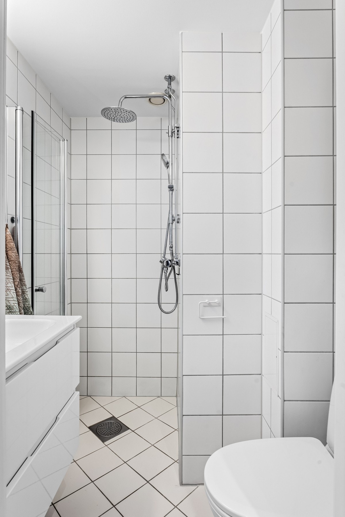 Dusjhjørnet har glassdører og en regnfallsdusj, mens toalettet er gulvstående. Galleribilde