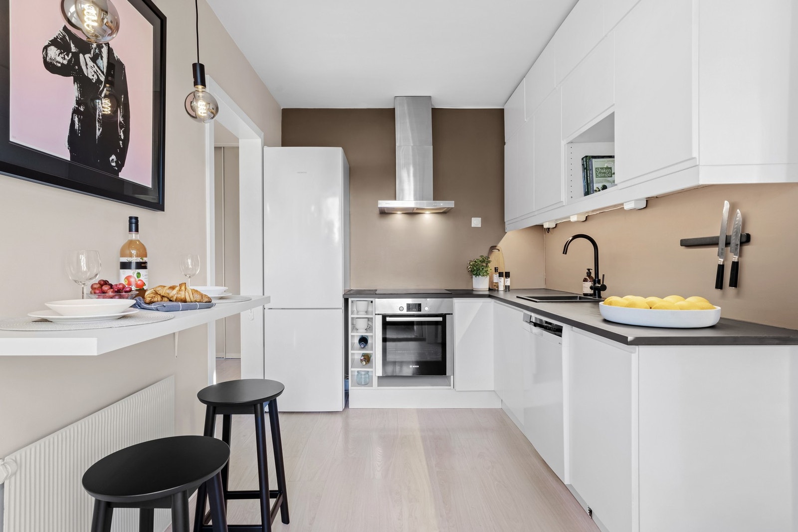 Det er integrert stekeovn og platetopp, frittstående kjøl/fryseskap og oppvaskmaskin med stålfront. Mikrobølgeovn er praktisk plassert i overskap Galleribilde