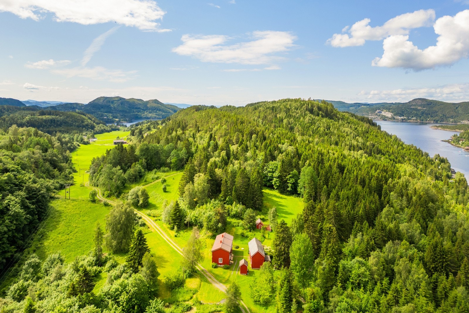 Eiendommen ligger lunt til, omkranset av frodig skog og grønne jorder - perfekt for deg som ønsker ro og naturskjønne omgivelser. Galleribilde