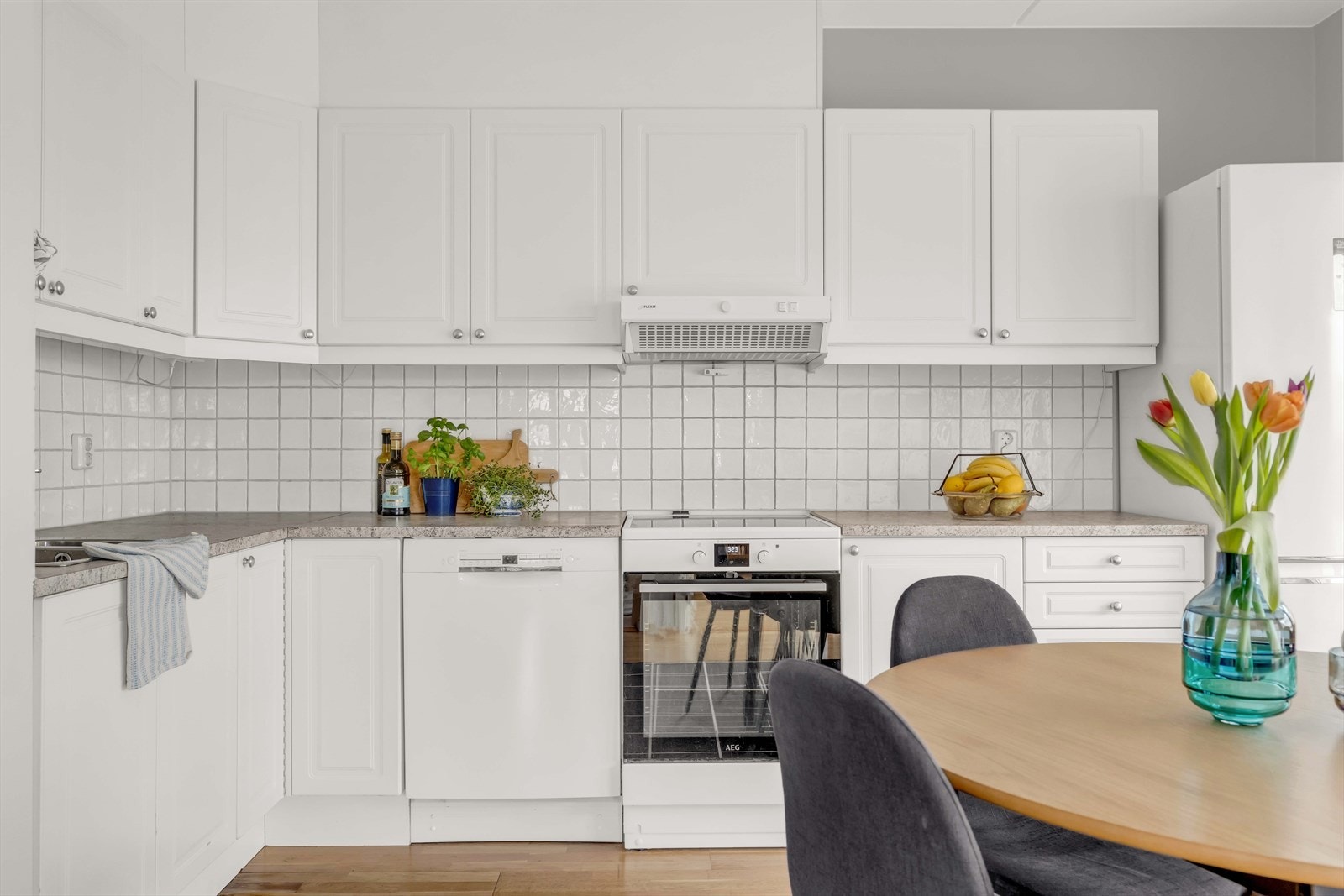 Kjøkkenet har et tidløst uttrykk med hvite fliser mellom benkeplate og overskap. Galleribilde