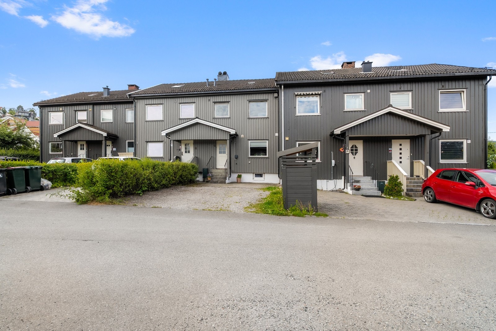 Plass til to biler på fremsiden av rekkehuset på gruset plass, delvis med belegningsstein. Galleribilde