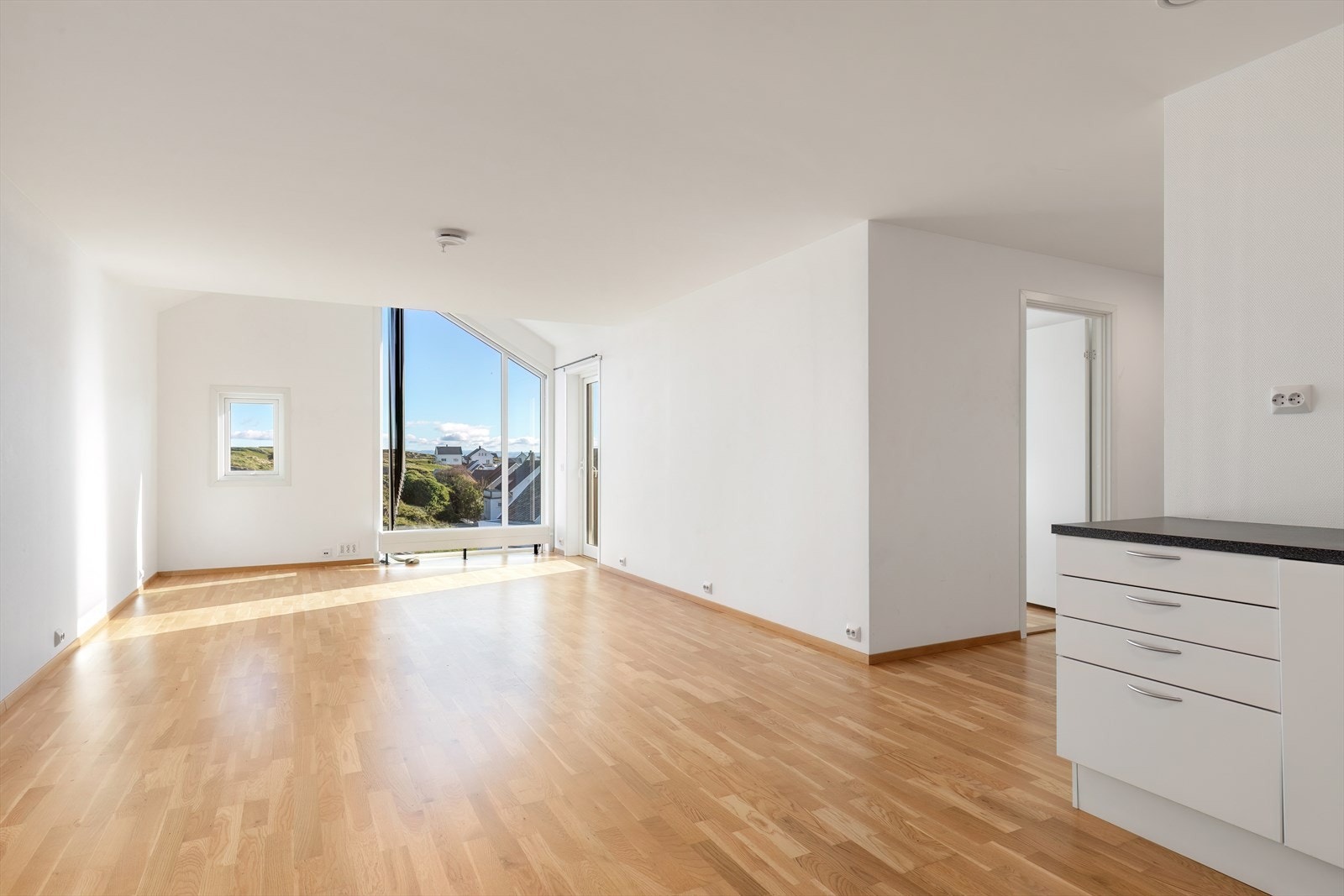 Store vindusflater i stuen gir utsyn mot grøntområde og slipper inn naturlig lys. Galleribilde