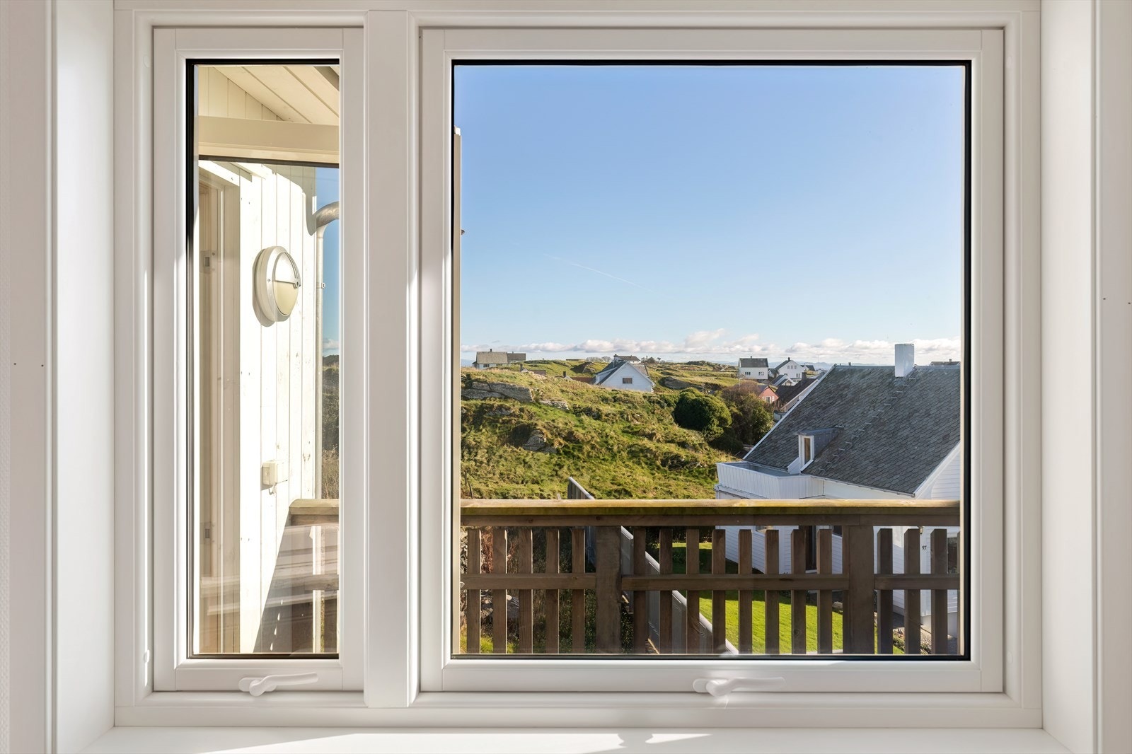 Utsikt gjennom vinduet viser et naturskjønt område med grønne omgivelser. Galleribilde