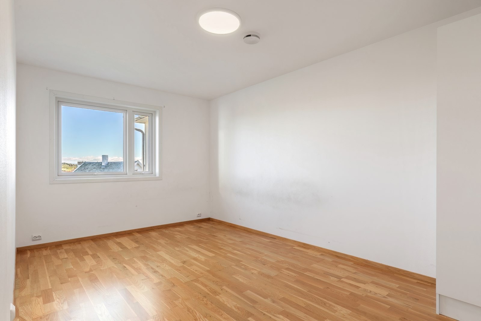 Parkettgulv og slettmalte vegger gir et rent uttrykk i soverommet. Galleribilde