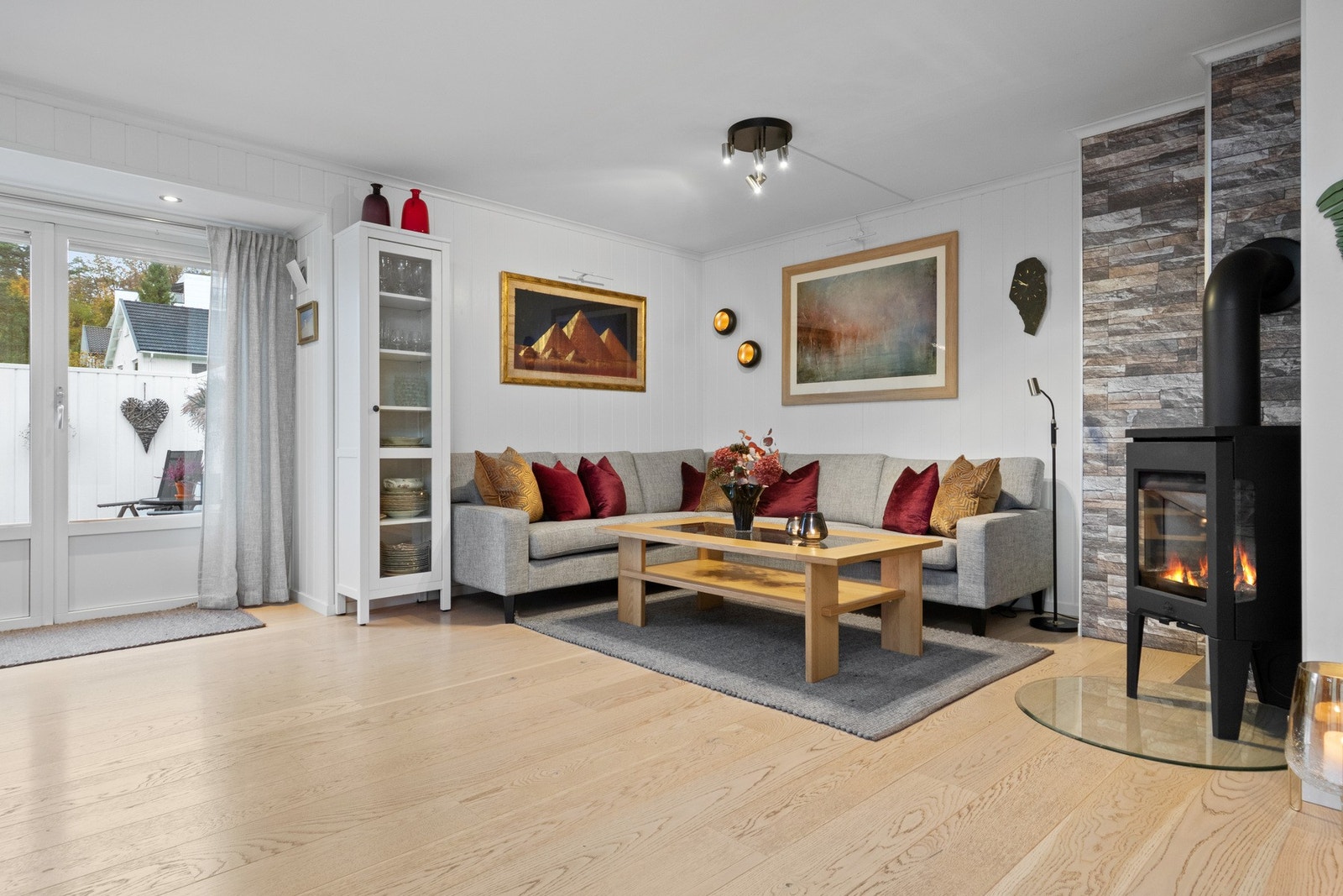 Stuen i hovedhuset er lun og innbydende, med peisovn og store vinduer som slipper inn dagslyset. Galleribilde