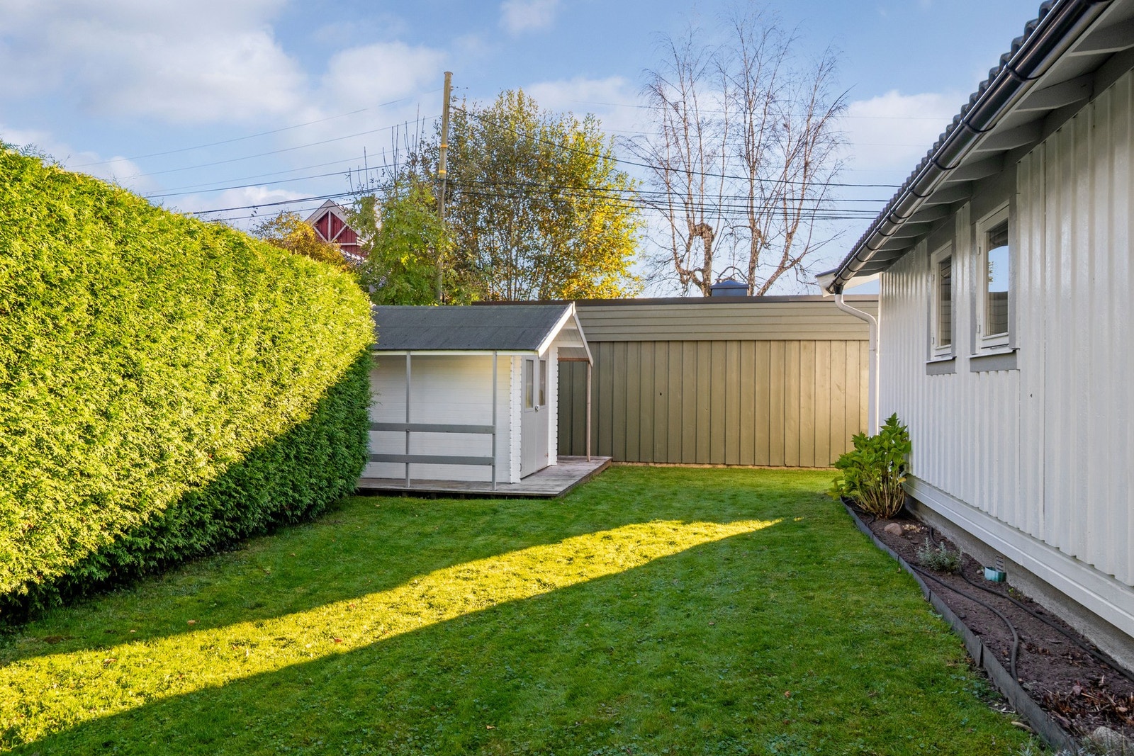 Bak hagen finner du et koselig hjørne med hekk og lite uthus. Galleribilde