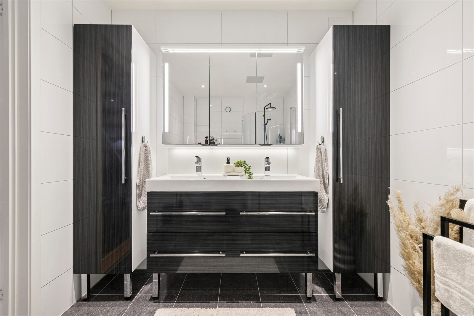 Rommet inneholder toalett, dusjnisje med glassdører, speil med lys, hvit servant nedfelt i skuffeseksjon Galleribilde