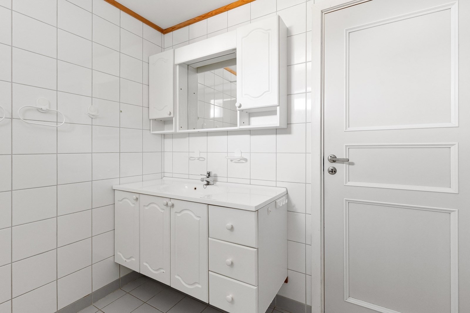 Rommet har innredning med profilerte fronter, servant med ettgreps armatur, veggskap og speil. Galleribilde