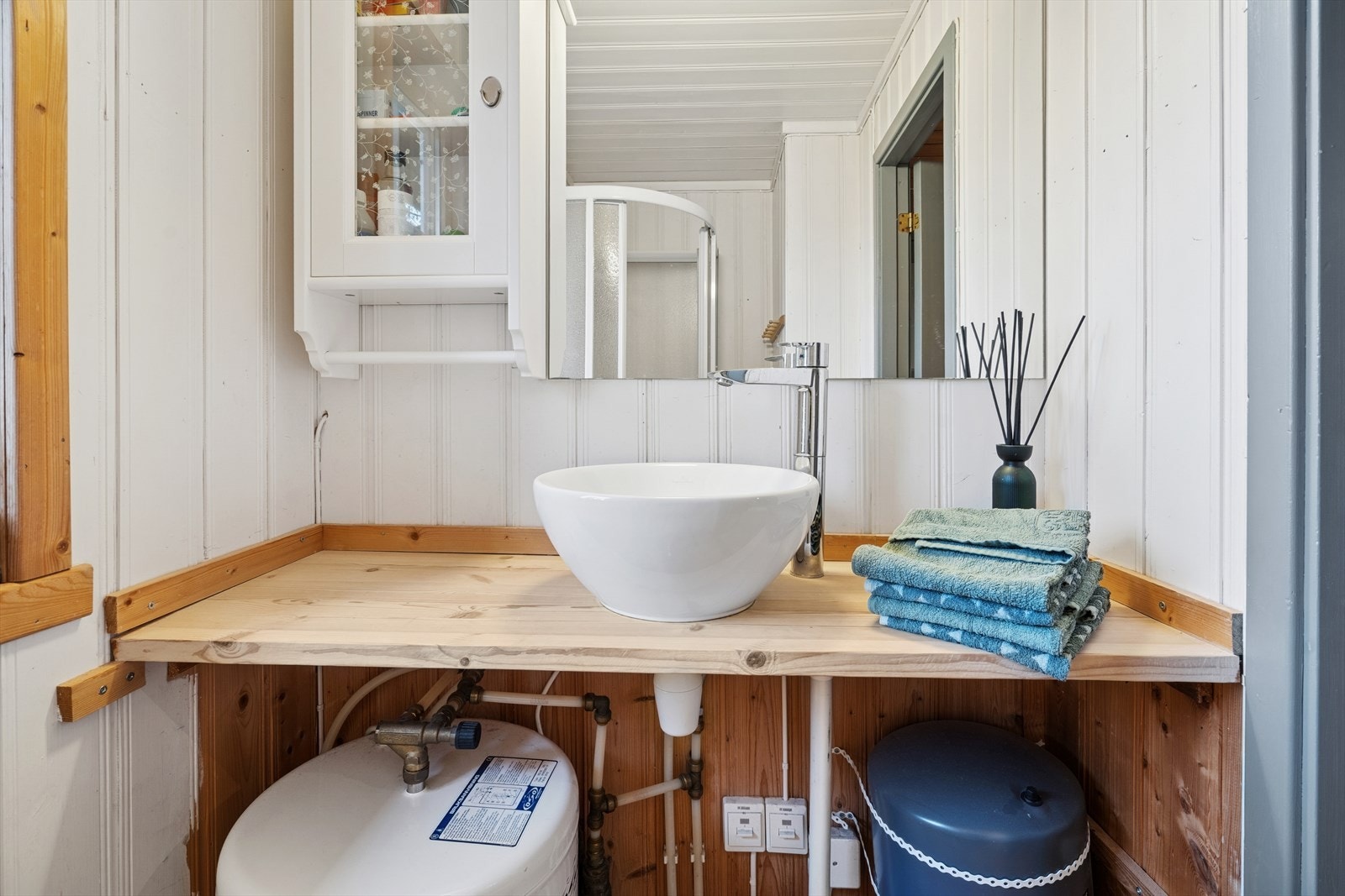 Hyttebad med montert dusjkabinett, elektrisk vifte og servant Galleribilde