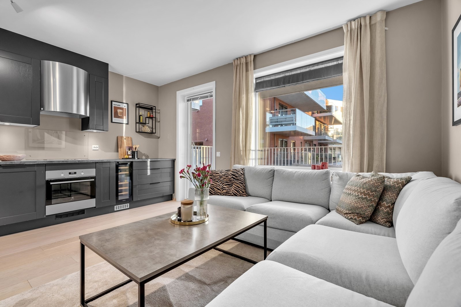 Den åpne og gjennomtenkte løsningen mellom stue og kjøkken gjør det enkelt å kombinere sosialt samvær og matlaging. Galleribilde