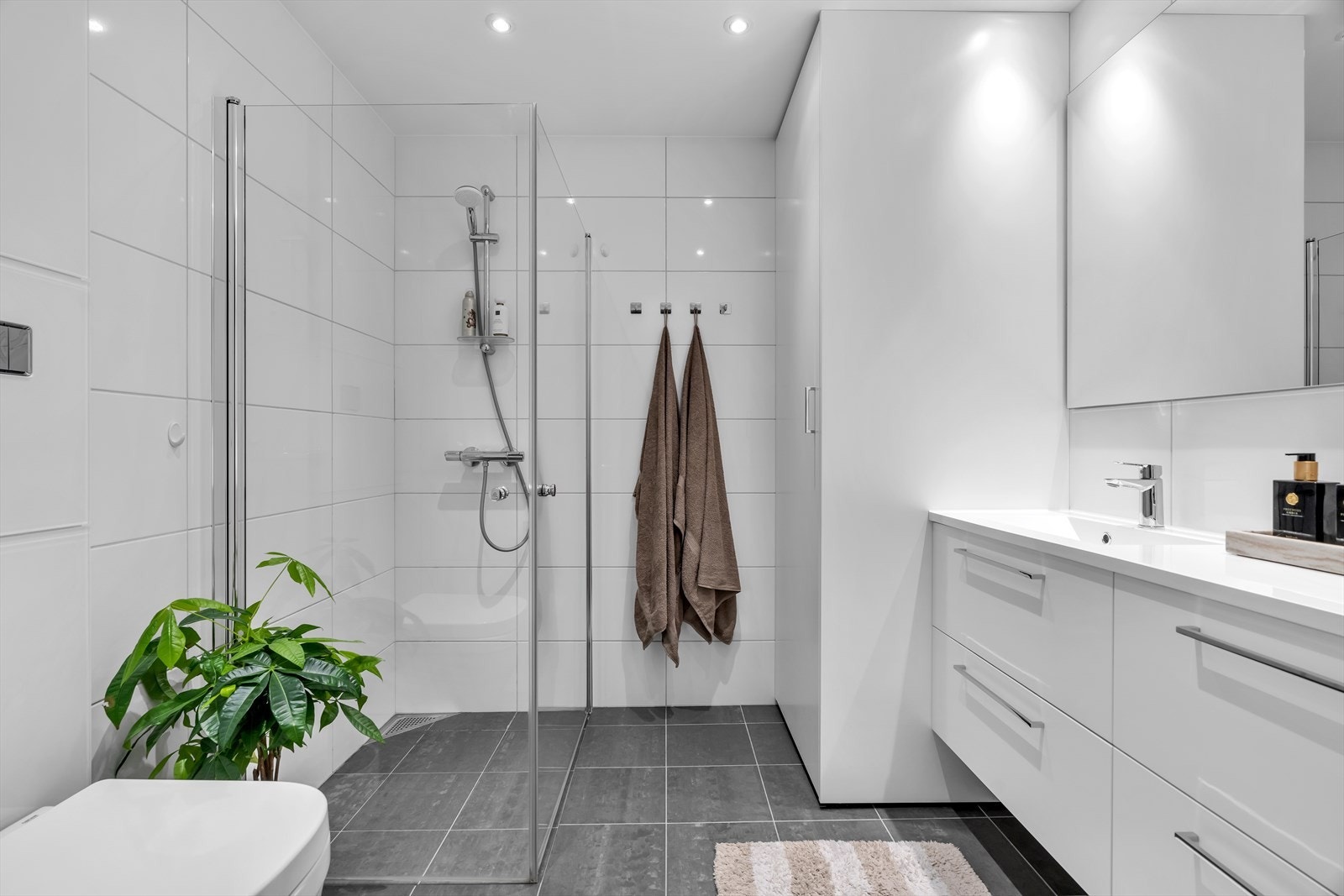 Dusjnisjen har plassbesparende glassvegger, og den stilrene innredningen består av servant med praktiske underskuffer. Galleribilde