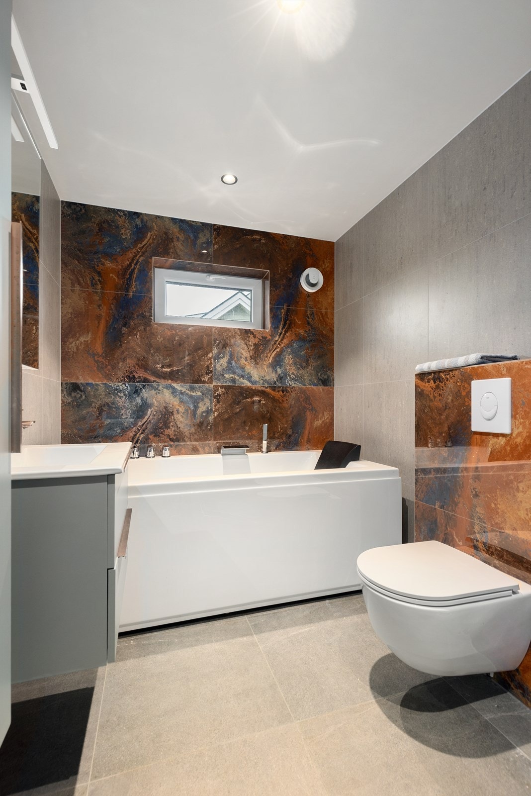 Delikat, flislagt bad i hovedetasjen pusset opp av fagfolk i 2023. Badet har varmekabler i gulv, veggmontert toalett, dusjkabinett og badekar. Galleribilde