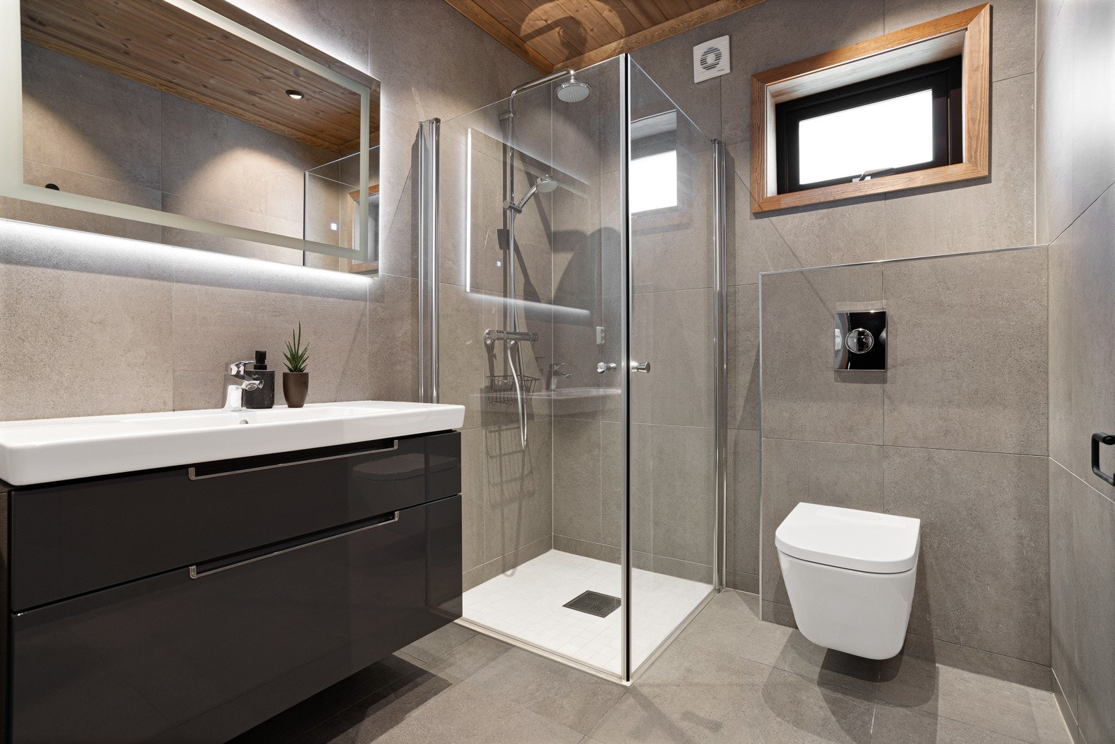 Hytta har to delikate og fullt utstyrte bad. Badene har store moderne fliser på vegg og gulv. Badet i 1.etasje er innredet med servant i innredning, speil med innfelt belysning, dusjnisje med regnfall-armatur og vegghengt toalett Galleribilde