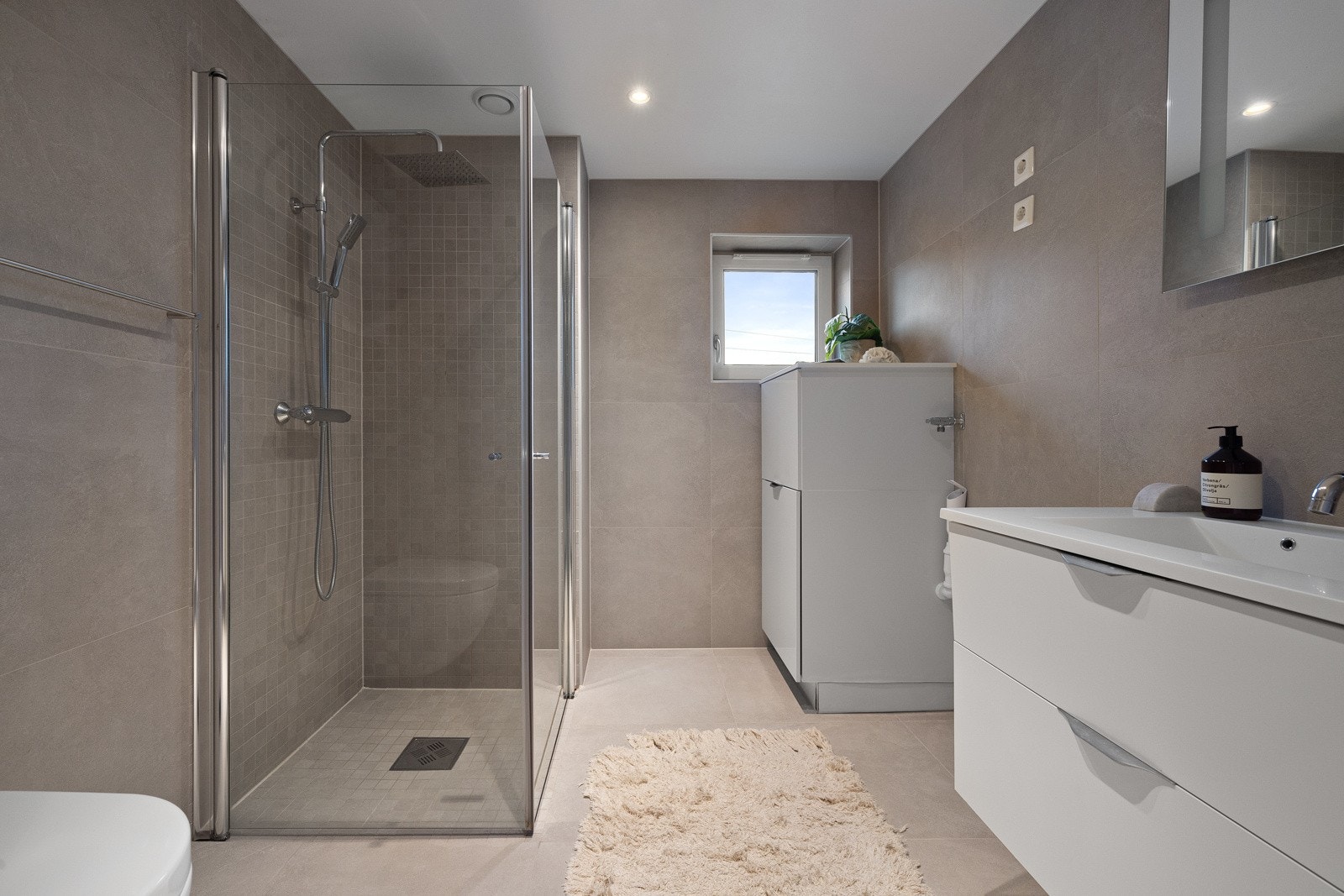 Lekkert flislagt bad med varmekabler, downlights og mekanisk avtrekk. Galleribilde