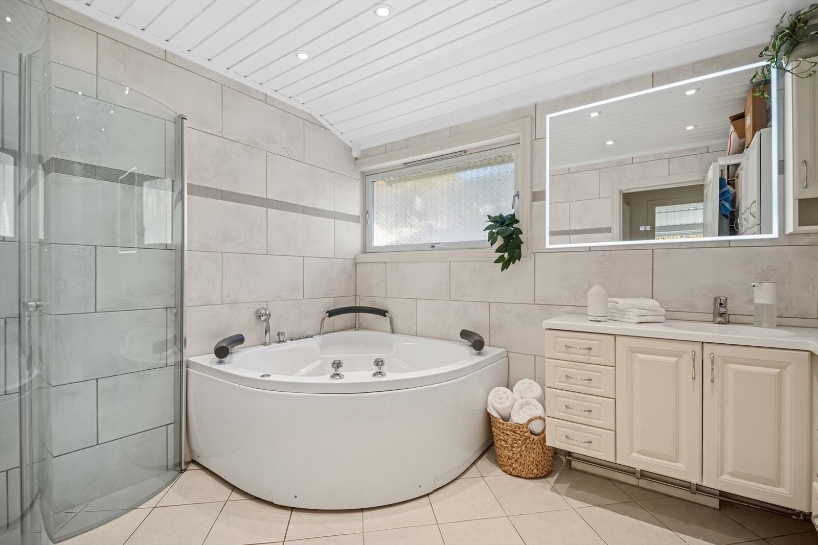 Delikat baderom med god plass, dusjløsning og innbydende hjørnebadekar for avslappende stunder Galleribilde