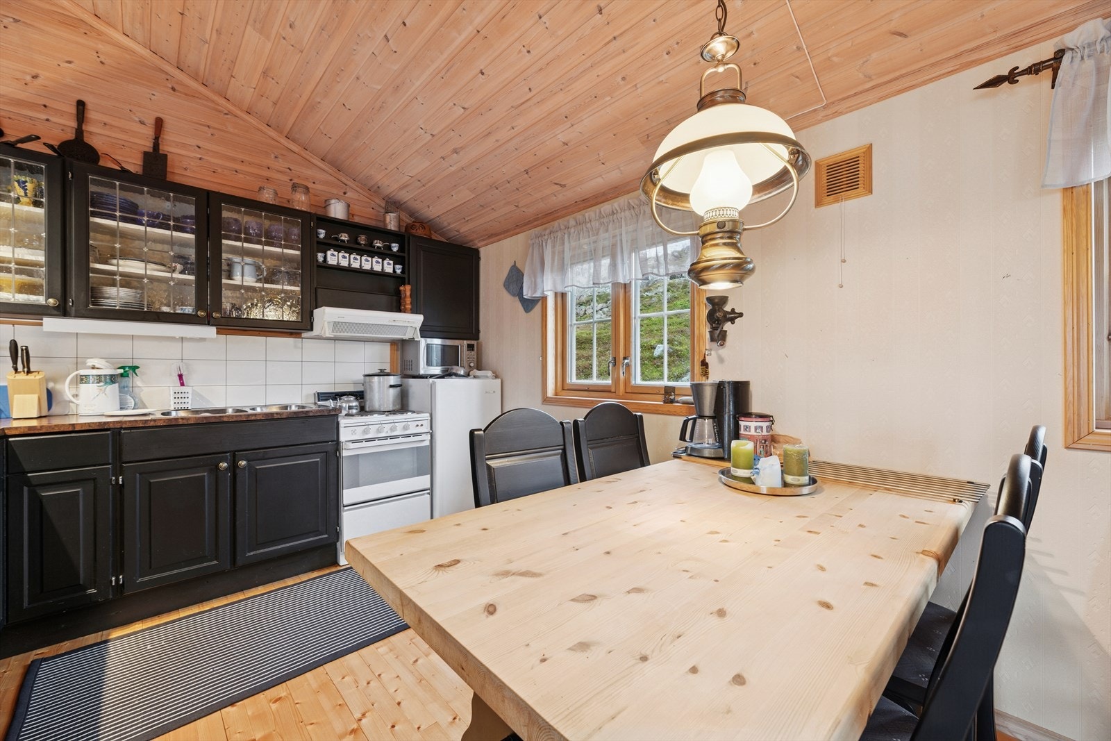 Kjøkkenet har en innredning med profilerte fronter, enkelte overskap med glassfelt og en benkeplate i laminat. Galleribilde